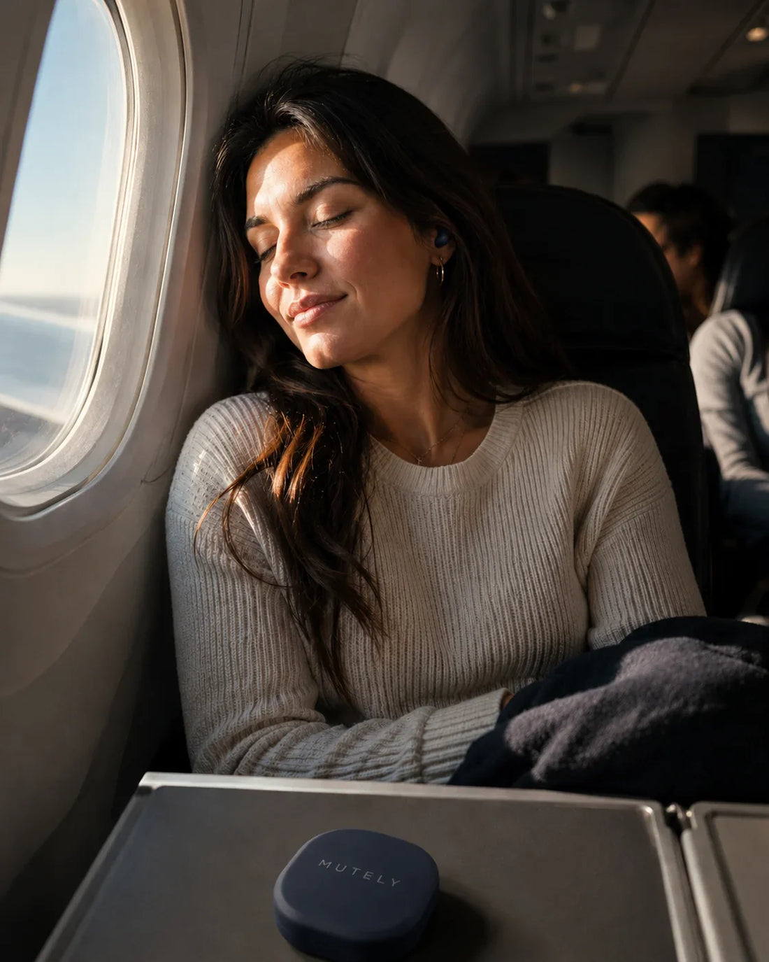 Jeune femme dormant près du hublot en avion avec étui de bouchons CORE bleu nuit